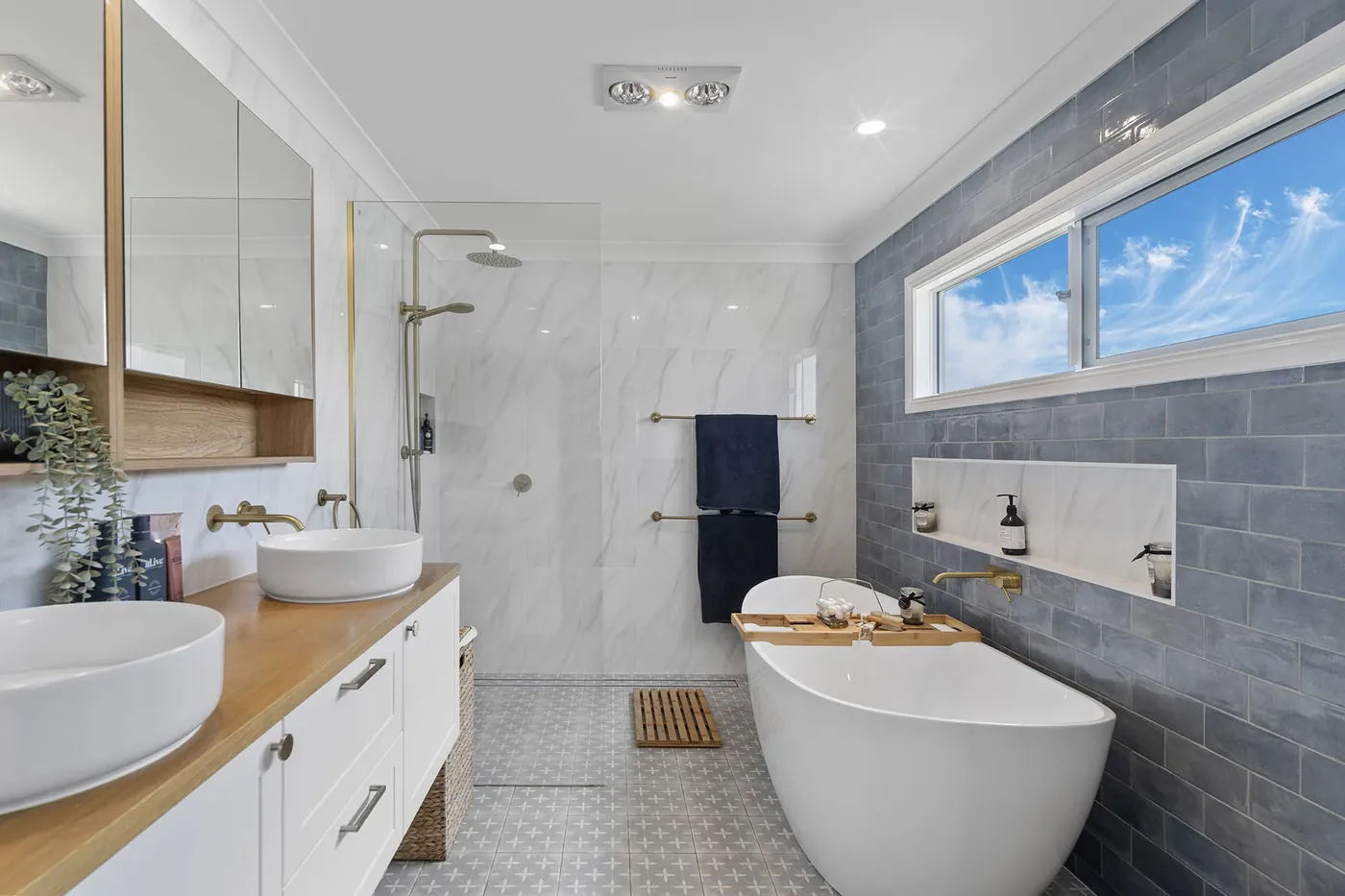 Bathroom with blue-grey feature tiling, a freestanding bath and timber-topped vanity.
