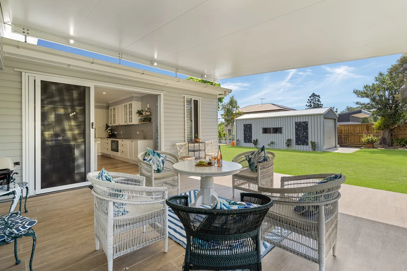 Covered outdoor dining space opening onto a lawn.