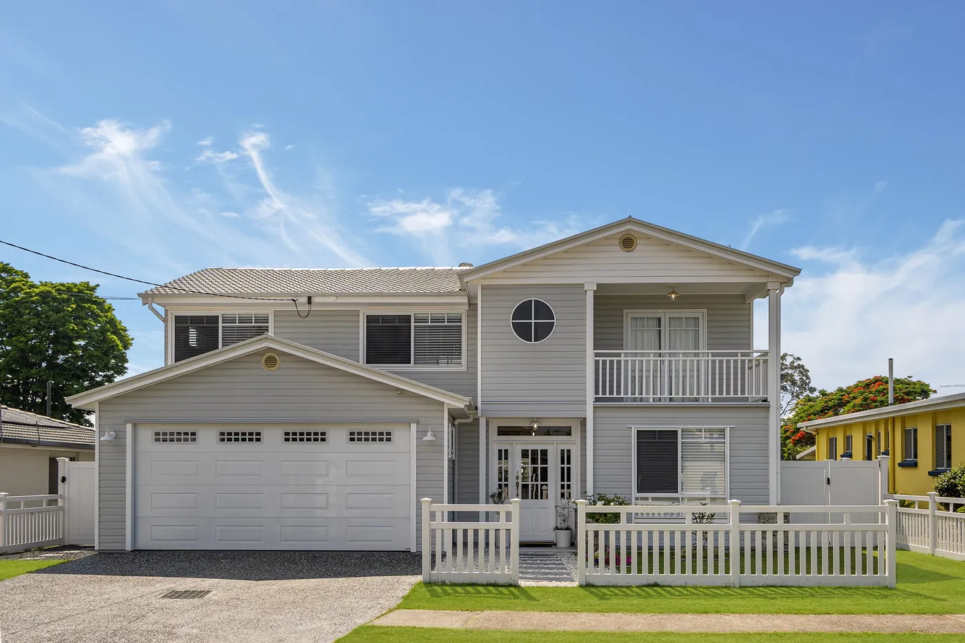 After renovation: the complete grey-and-white house frontage with garage, balcony and welcoming entry.