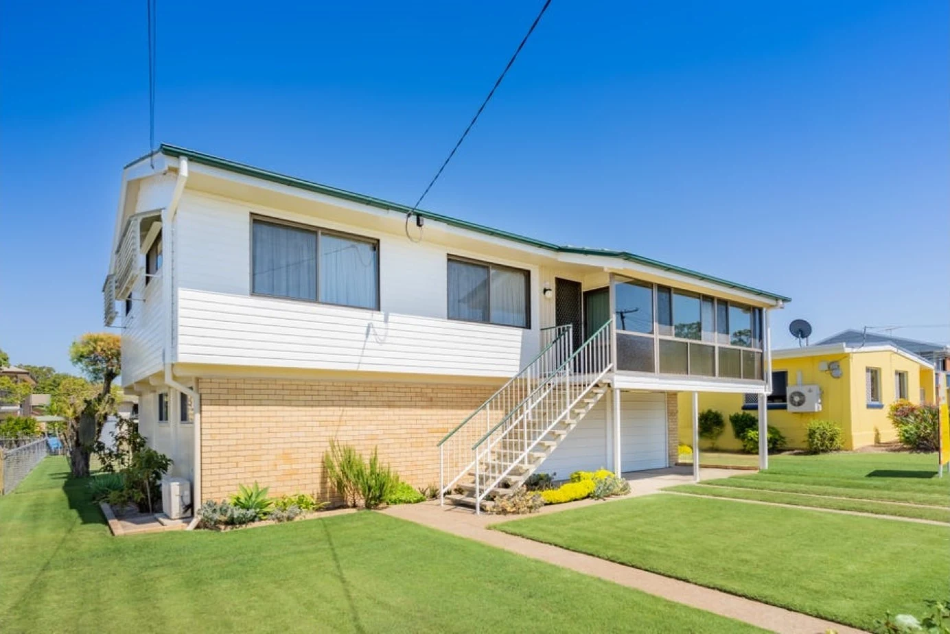 Before renovation: the original raised house with exterior stairs and enclosed front verandah.