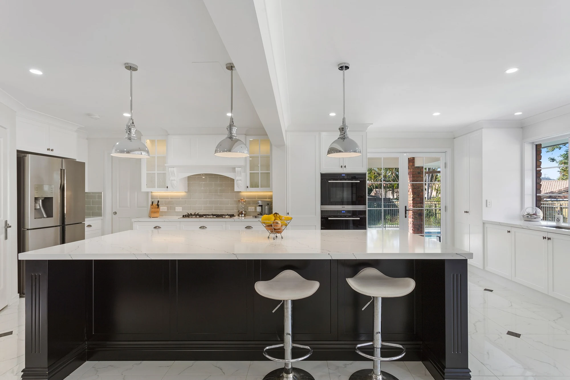 White kitchen with a contrasting black island and pendant lighting.