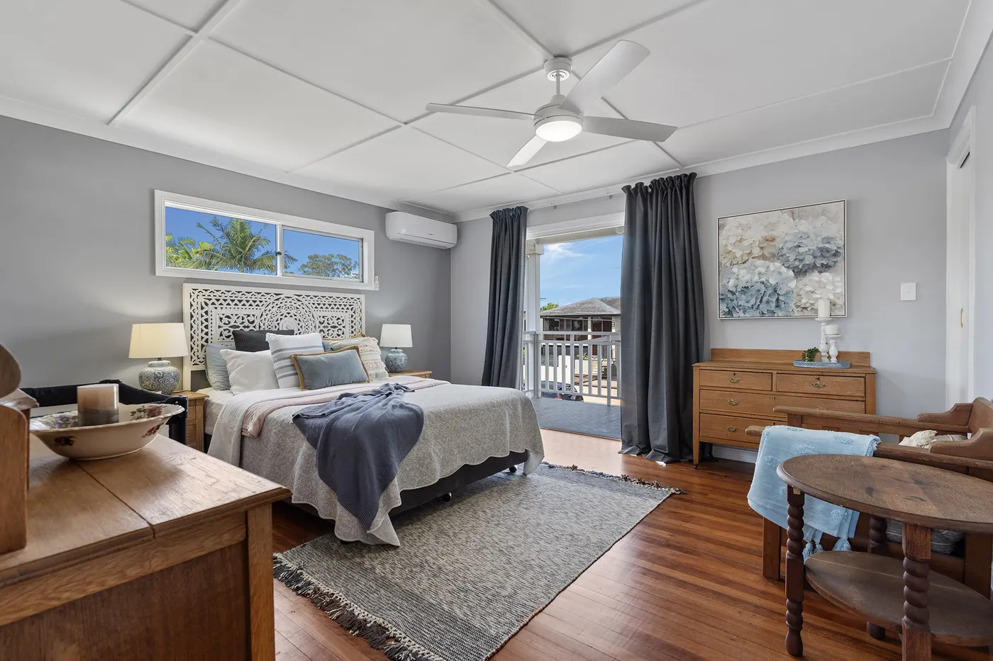 Bedroom with timber furniture, grey walls and balcony access.